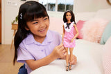Poupée Barbie Fashionistas avec cheveux noirs et bandeau de perles portant une robe à carreaux rose avec nœud noir et col à volants pour 3 ans et plus HJT06
